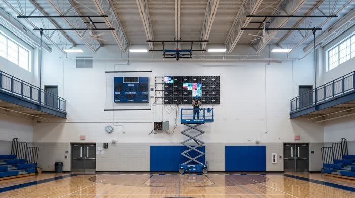 Installer on a lift mounting gym LED wall panels